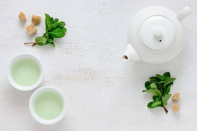 white teapot, 2 teacups, and green tea